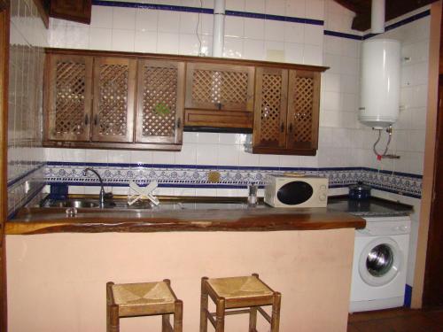 a kitchen with a sink and two stools at Casa Rural La Ortiga in Robledillo de Gata