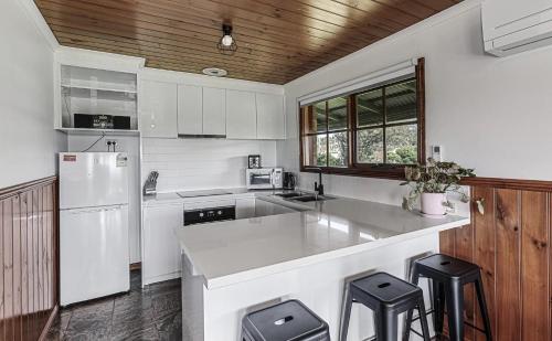 una cucina con mobili bianchi e un frigorifero bianco di Apollo Bay Cottages- Sabine a Marengo