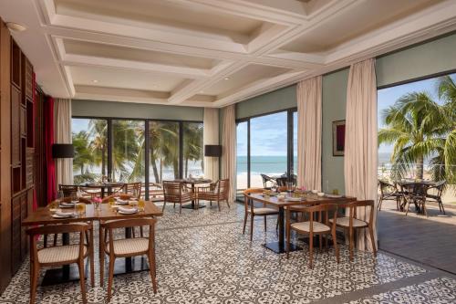uma sala de jantar com mesas e cadeiras e o oceano em Melia Ho Tram Beach Resort em Ho Tram