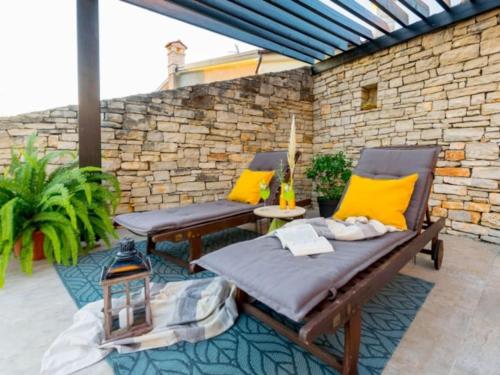 a patio with two chairs and a table with yellow pillows at Villa Macan by IstriaLux in Svetvinčenat