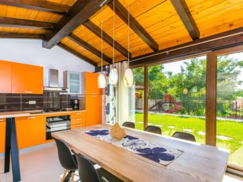 an orange kitchen with a wooden table and chairs at Villa Macan by IstriaLux in Svetvinčenat