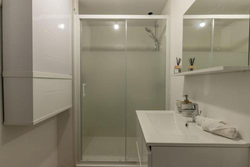 a white bathroom with a shower and a sink at L'Appart des Platanes in Romorantin