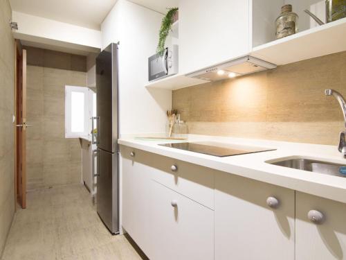 a kitchen with white cabinets and a stainless steel refrigerator at Chezmoihomes Apartment Cathedral 2 dormitorios in Granada