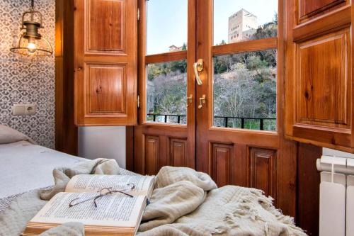 sypialnia z książką na łóżku z oknem w obiekcie Luxury Alhambra Hideaway w Grenadzie