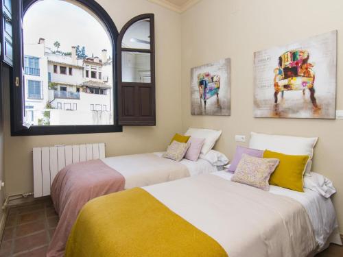 two beds in a room with two windows at Mirador de los arcos Alhambra in Granada