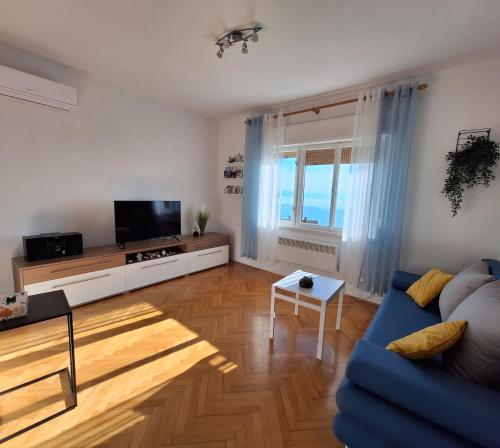 een woonkamer met een blauwe bank en een televisie bij Apartmani Marini in Opatija