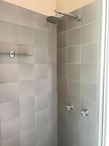 y baño con ducha de azulejos blancos. en triple S guest house, en Ciudad del Cabo