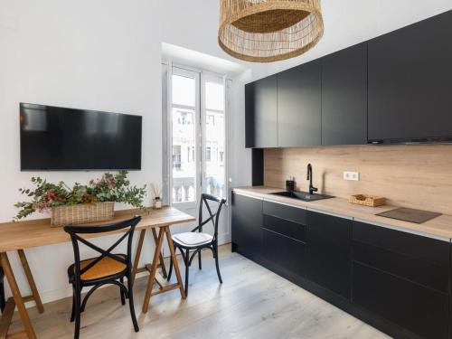 a kitchen with black cabinets and a table and chairs at Bright and Elegant Gran Via apartments in Granada