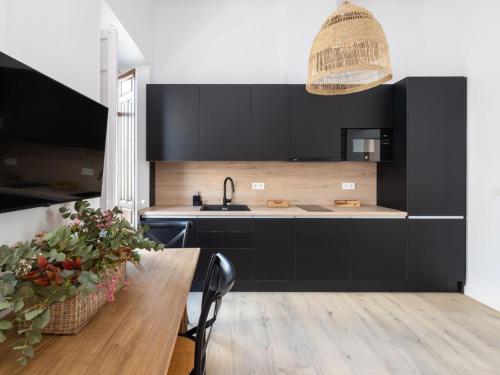 cocina con armarios negros y mesa de madera en Bright and Elegant Gran Via apartments, en Granada