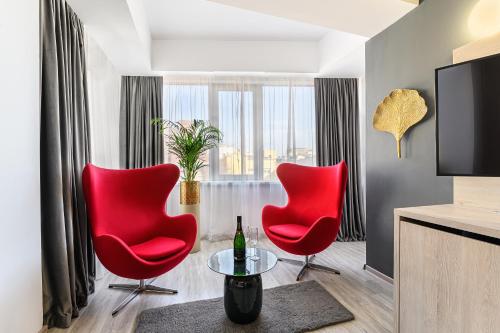 a living room with two red chairs and a tv at Unique Boutique in Bucharest