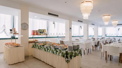 a restaurant with white tables and white chairs and food at Hotel Baltic in Misano Adriatico