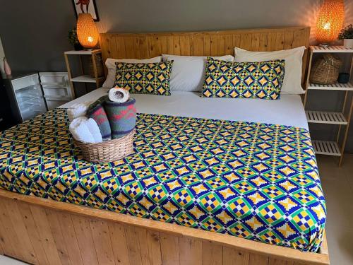 a bed with a wooden frame with a blanket and a basket at African Treasure Beach Resort in Kokrobite