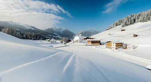 a snow covered road with a village in the mountains at Sonnenappartements Madlstatthof in Wildschönau
