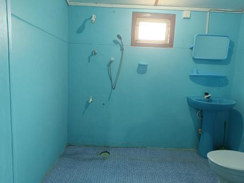 een blauwe badkamer met een toilet en een raam bij Vijay Thulasi Beach View in Nilaveli