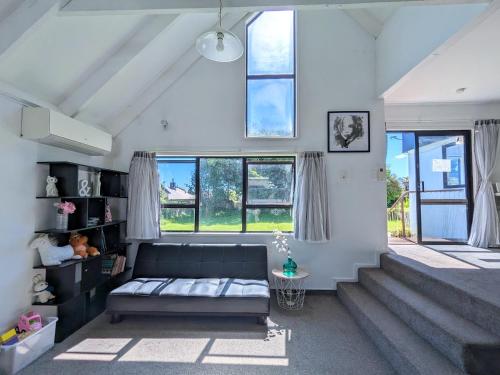 a living room with a couch and some windows at Rotorua redwood retreat in Rotorua