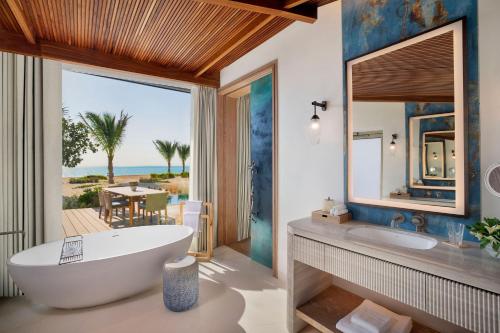 baño con bañera y vistas al océano en The St. Regis Red Sea Resort, en Ḩanak