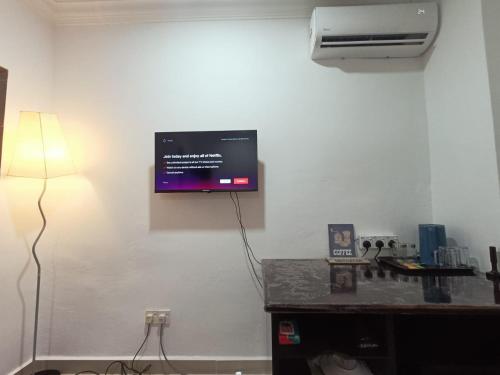 een kamer met een tv aan een muur met een lamp bij SELESA GUEST RoOM in Skudai