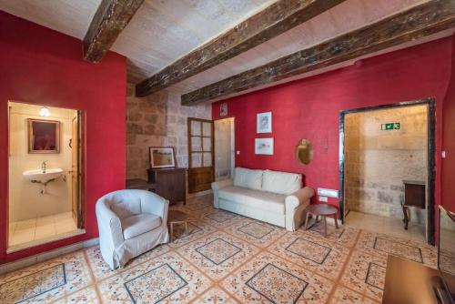 ein Wohnzimmer mit roten Wänden, einem Sofa und Stühlen in der Unterkunft Vallettastay Standard Apartments in Valletta in Valletta