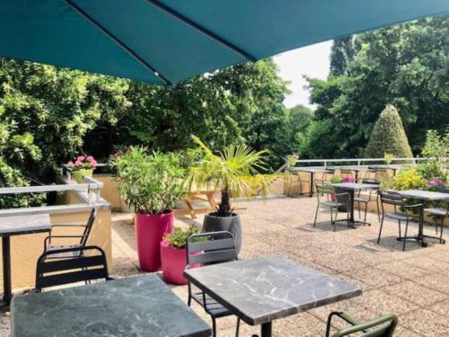a patio with tables and chairs and potted plants at B&B HOTEL Chartres Centre Cathédrale 3 étoiles in Chartres