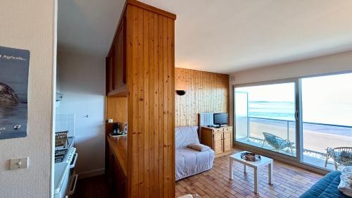 un salon avec un canapé et une grande fenêtre dans l'établissement Studio avec balcon, vue panoramique sur la baie, au Crotoy