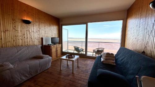 un salon avec un canapé et une grande fenêtre dans l'établissement Studio avec balcon, vue panoramique sur la baie, au Crotoy