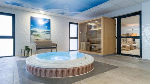 ディーブ・シュル・メールにあるKyriad Prestige Residence & Spa Cabourg-Dives-sur-Merのホットタブが備わる広い客室です。