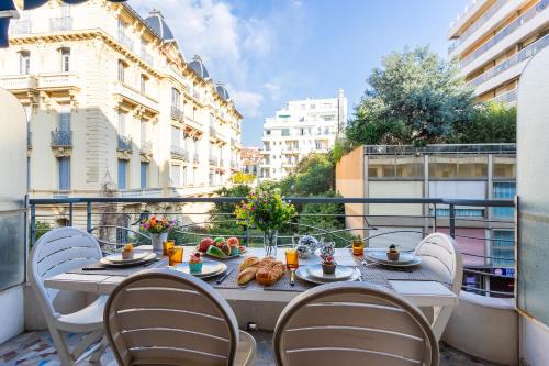 - une table avec des chaises et de la nourriture sur le balcon dans l'établissement LE FRANCE-MASSENET AP3015 by Riviera Holiday Homes, à Nice