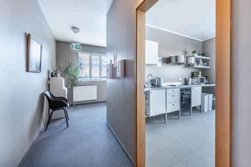 a kitchen with white cabinets and a chair in a room at Stöð Guesthouse and apartments in Grundarfjordur
