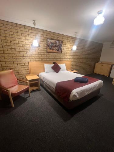a bedroom with a large bed and a chair at OVERLANDER MOTOR LODGE in Gunnedah