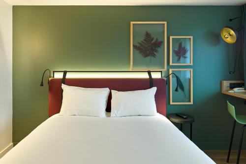 a bed with white pillows in a room at Campanile Villennes-Sur-Seine - Poissy - Hôtel rénové en 2024 in Villennes-sur-Seine