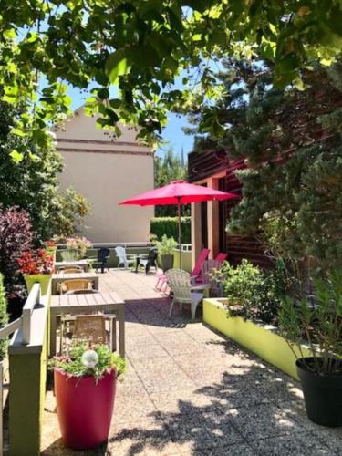 a patio with a table and a red umbrella at B&B HOTEL Chartres Centre Cathédrale 3 étoiles in Chartres