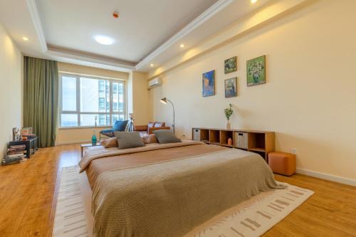 sypialnia z dużym łóżkiem i dużym oknem w obiekcie Dalian Baobab Apartment w mieście Dalian