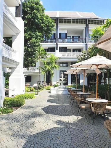 a patio with tables and umbrellas in front of a building at Buri Sriping Riverside Resort & Spa in Chiang Mai