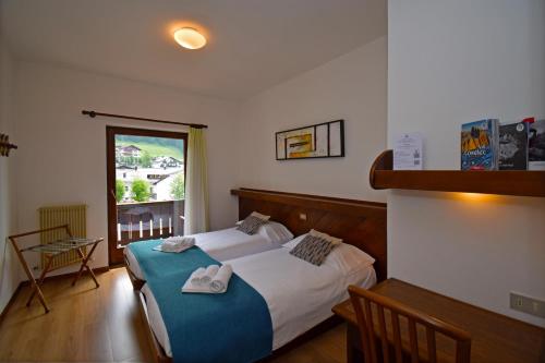 1 dormitorio con 1 cama con toallas en Hotel Comelico, en Padola