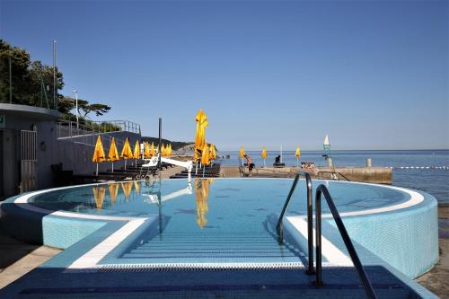a swimming pool next to the ocean with umbrellas at Depandansa Vista Parco, Izola in Izola
