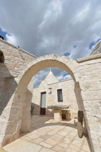 a stone building with an arch in front of it at Masseria Pentima Vetrana Resort in Alberobello