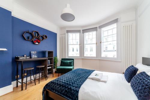 Schlafzimmer mit blauen Wänden, einem Bett und einem Schreibtisch in der Unterkunft Cannon Street Studios in London