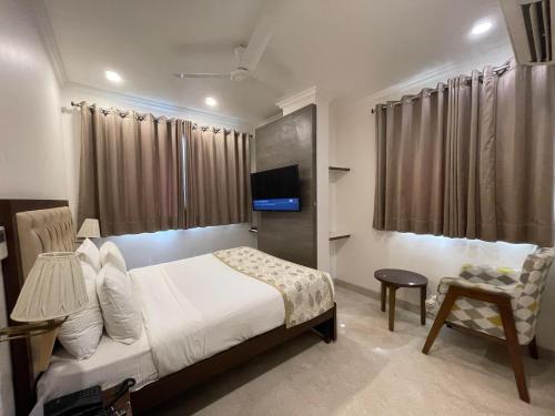 a bedroom with a bed and a tv and a chair at Wongdhen House in New Delhi