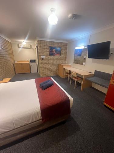 a hotel room with a bed and a table and a desk at OVERLANDER MOTOR LODGE in Gunnedah