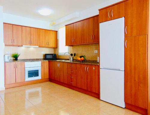 cocina con armarios de madera y nevera blanca en Brisa Del Mar Fuerteventura en Puerto del Rosario