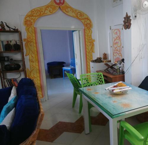 a living room with a table and green chairs at Casa di Mara in Puttaparthi