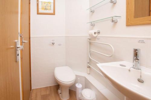 a white bathroom with a toilet and a sink at Chalet 98 in Deal