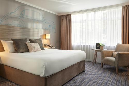a hotel room with a large bed and a chair at Leonardo Royal Hotel Oxford in Oxford