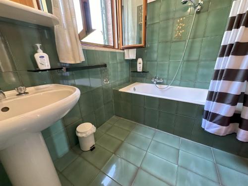 ein grün gefliestes Badezimmer mit einem Waschbecken und einer Badewanne in der Unterkunft Villa Chris in Taormina