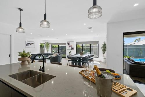 a kitchen with a sink and a living room at The Palms Guest House Yarrawonga in Yarrawonga