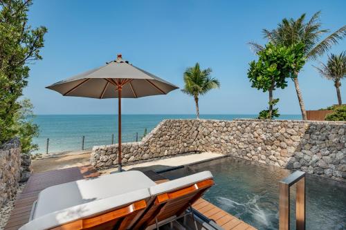a patio with an umbrella and a swimming pool and the ocean at Casa De La Flora - SHA Extra Plus in Khao Lak