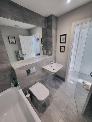 a bathroom with a sink and a toilet and a tub at Private room in townhouse near Heathrow & Windsor in Burnham