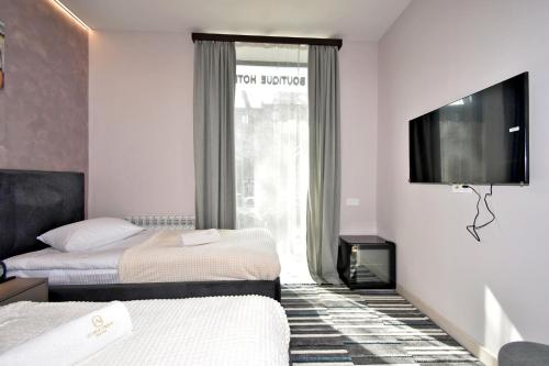 a hotel room with two beds and a flat screen tv at Avenue 23 Boutique Hotel in Yerevan