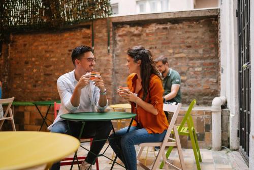佛羅倫斯的住宿－Foresteria Sociale Florence Center by New Generation Hostel，坐在桌子上喝饮料的男人和女人