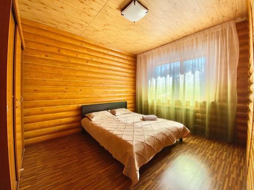 - une chambre avec un lit dans une pièce en bois dotée d'une fenêtre dans l'établissement Сакский Двор, à Besqaynar